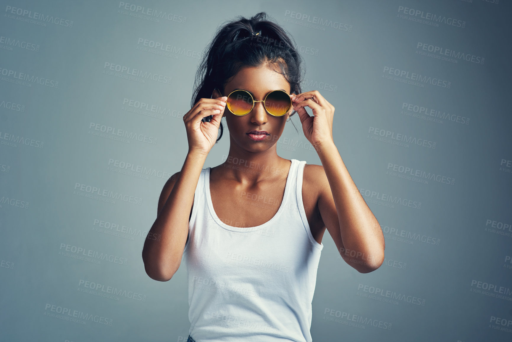 Buy stock photo Hands, fashion and woman with sunglasses in studio for confidence, designer eyewear or trendy style on blue background. Gen z, cool and Indian model with glasses for glamour, accessories and mockup