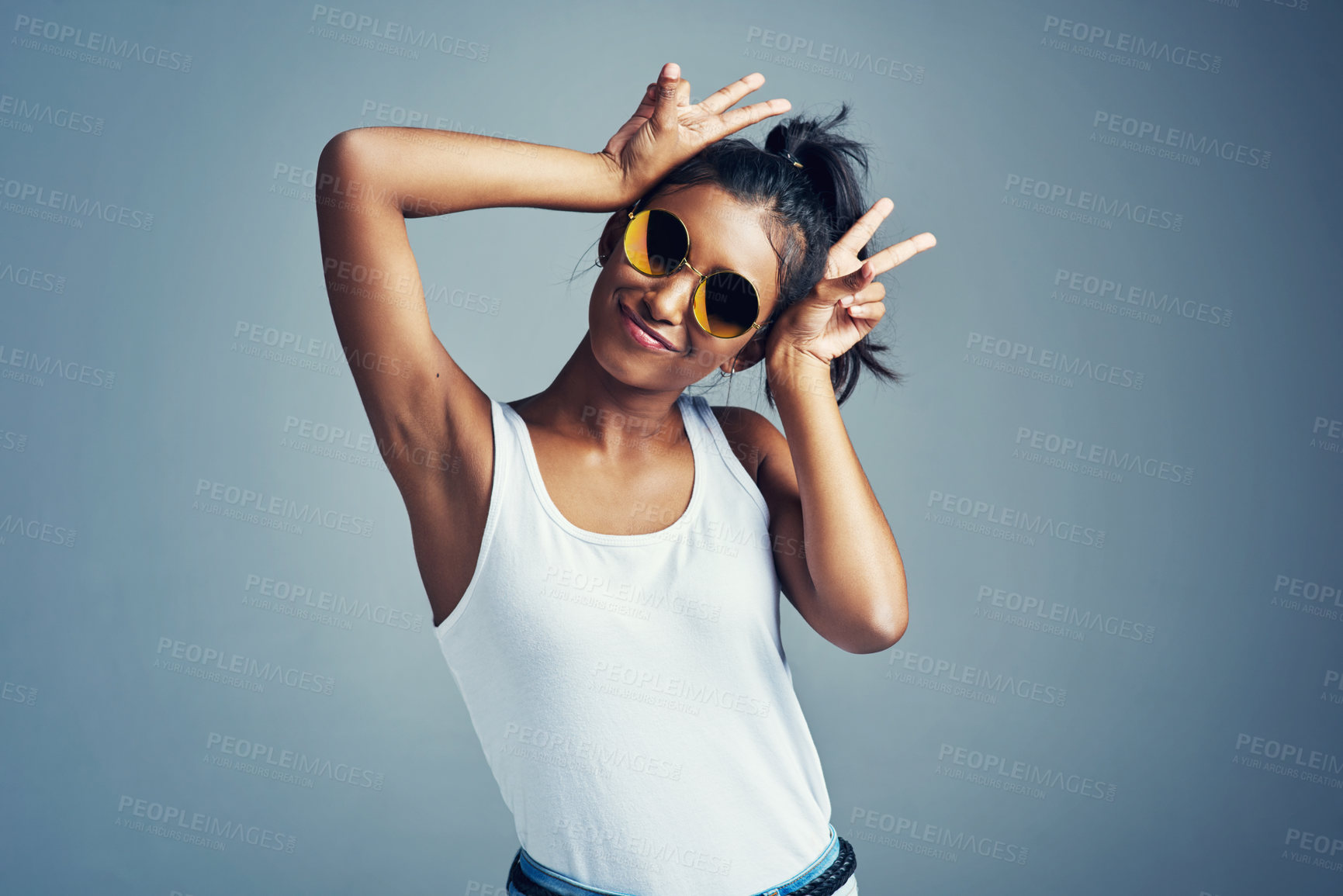 Buy stock photo Studio portrait of a beautiful young woman gesturing with bunny ears against a grey background