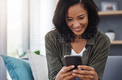 Buy stock photo Shot of an attractive young woman using a smartphone on the sofa at home