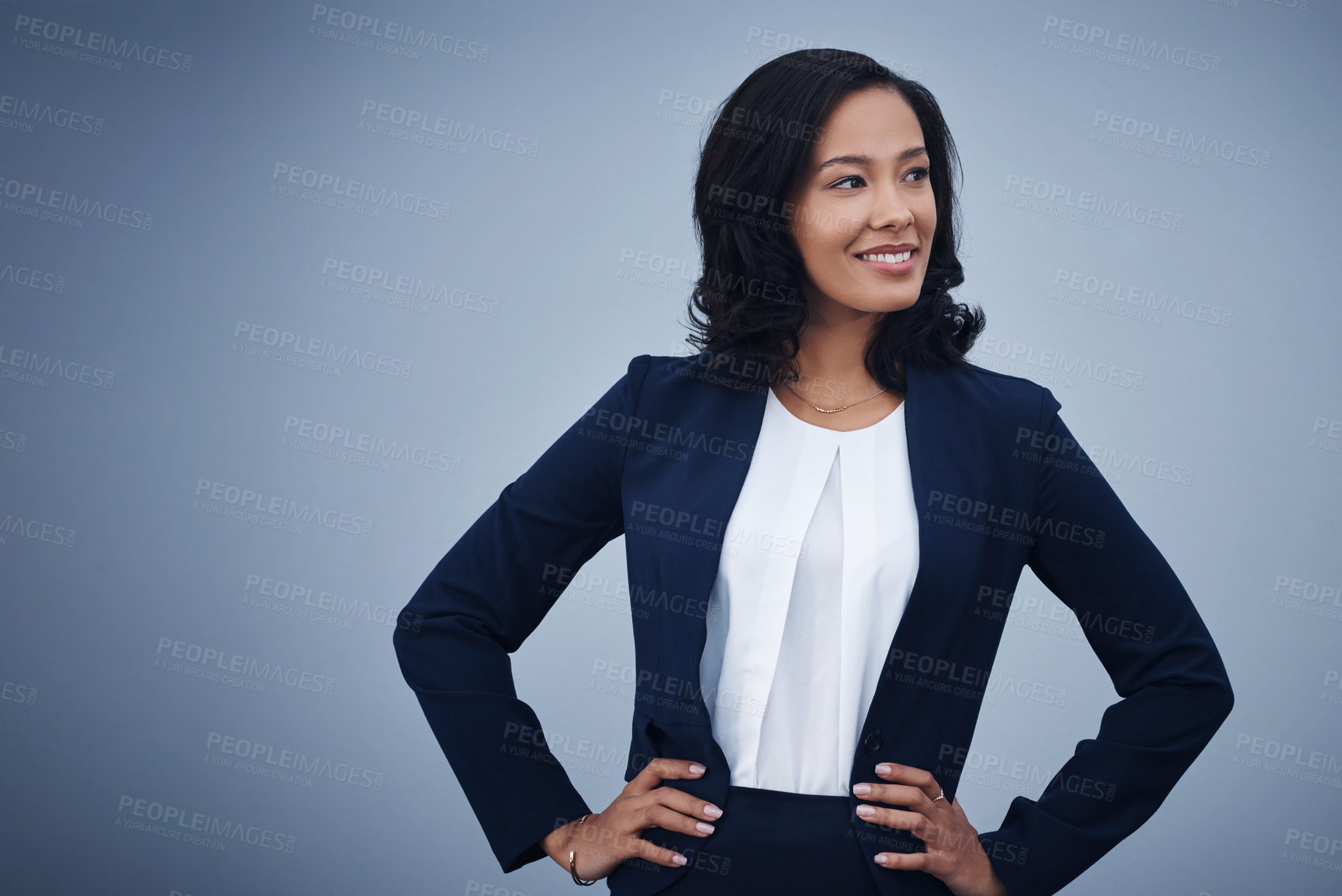 Buy stock photo Studio shot of a young businesswoman standing with her hands on her hips against a grey background