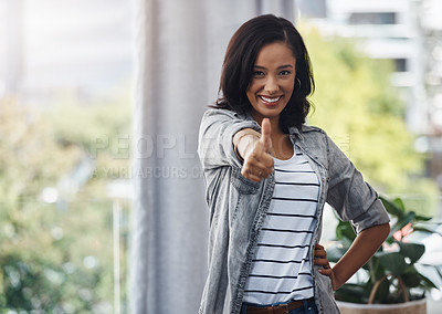 Buy stock photo Portrait of a young woman showing thumbs up at home
