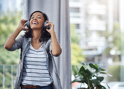 Buy stock photo Shot of a young woman wearing headphones while listening to music at home
