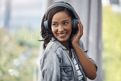 Buy stock photo Shot of a young woman wearing headphones while listening to music at home