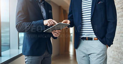 Buy stock photo Cropped shot of two businessmen using a digital tablet together in a modern office