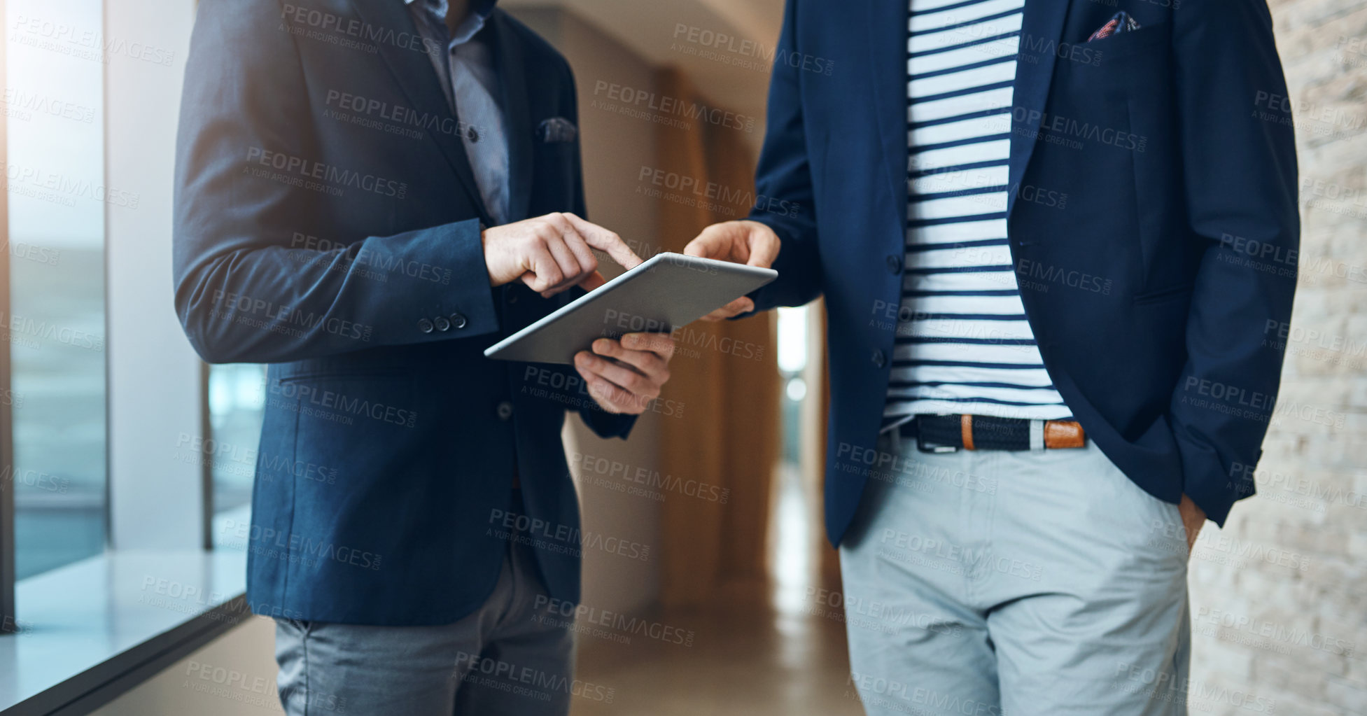 Buy stock photo Cropped shot of two businessmen using a digital tablet together in a modern office