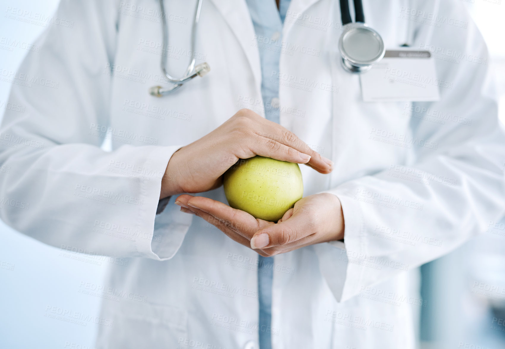 Buy stock photo Closeup shot of an unrecognizable doctor holding an apple in her hands