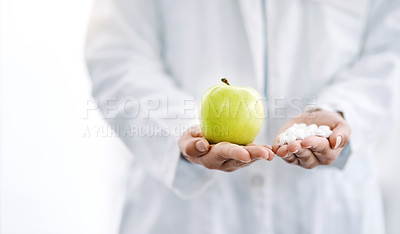Buy stock photo Closeup shot of an unrecognizale doctor holding an apple and a variety of pills in her hands