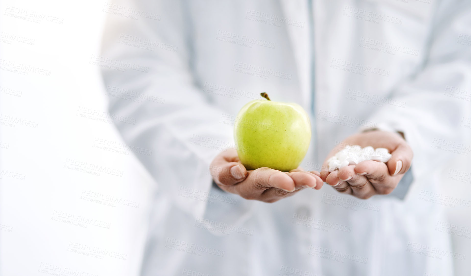 Buy stock photo Closeup shot of an unrecognizale doctor holding an apple and a variety of pills in her hands