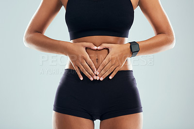 Buy stock photo Studio shot of an unrecognizable sporty woman forming a heart shape on her stomach against a grey background