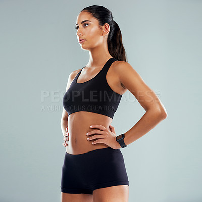 Buy stock photo Studio shot of an athletic young woman posing with her hands on her hips against a grey background
