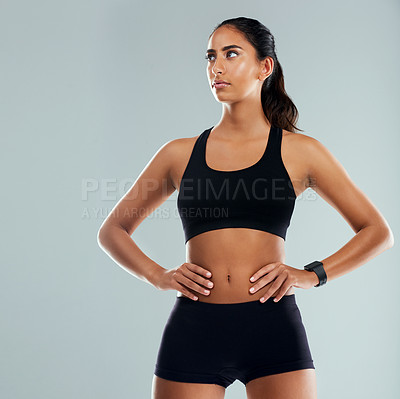 Buy stock photo Studio shot of an athletic young woman posing with her hands on her hips against a grey background