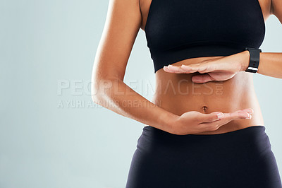 Buy stock photo Studio shot of an unrecognizable sporty woman framing her stomach with her hands against a grey background