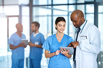 Buy stock photo Shot of two of medical practitioners using a digital tablet together in a hospital