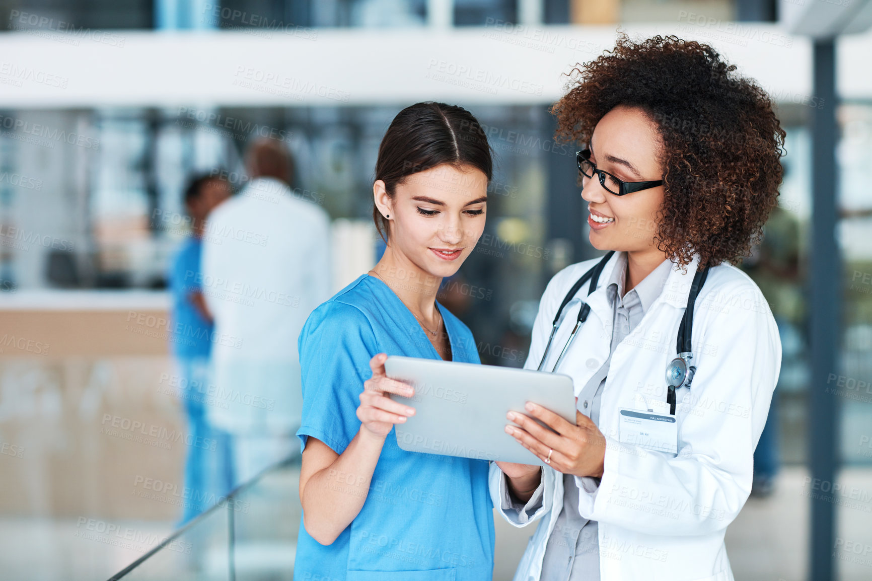 Buy stock photo Shot of two medical practitioners using a digital tablet together in a hospital