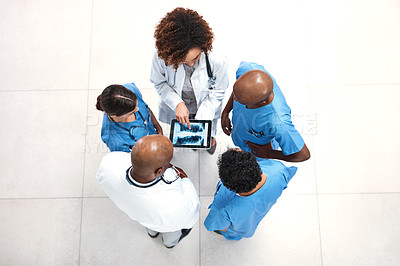 Buy stock photo High angle shot of a group of medical practitioners looking at x-ray scans on a digital tablet in a hospital