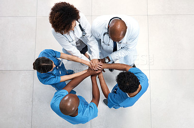 Buy stock photo High angle shot of a group of medical practitioners joining their hands together in a huddle