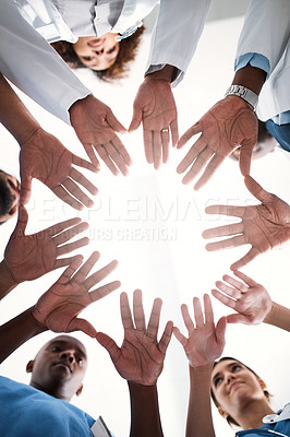 Buy stock photo Low angle shot of a group of medical practitioners joining their hands together in a hospital