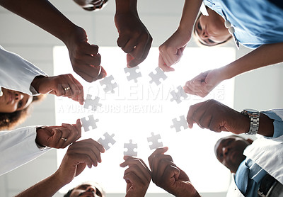 Buy stock photo Low angle shot of a group of medical practitioners joining puzzle pieces together