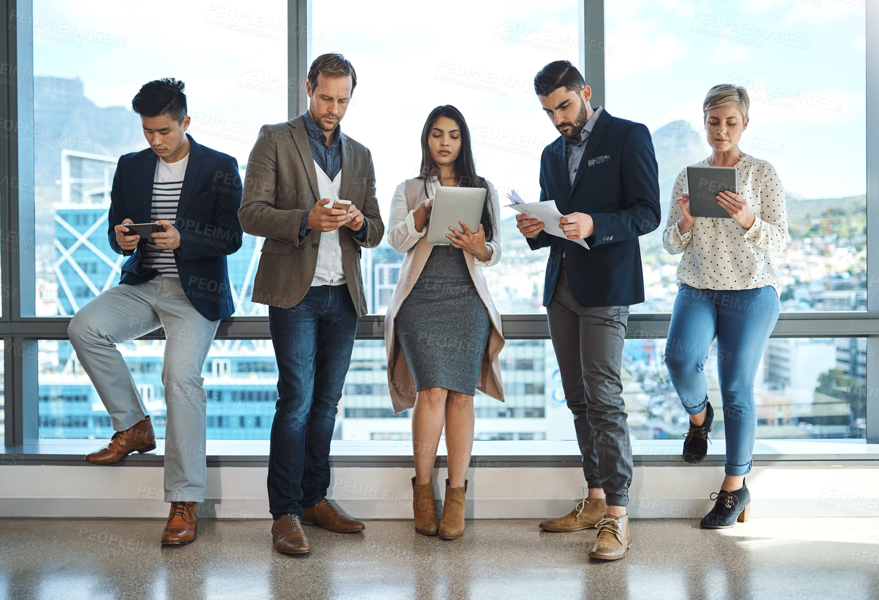 Buy stock photo Full length shot of a diverse group of businesspeople using wireless technology in an office