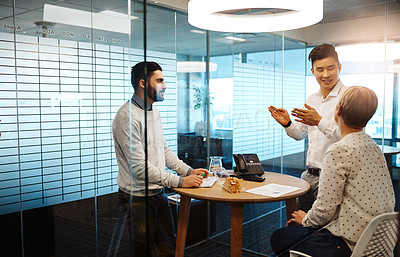 Buy stock photo Cropped shot of three young businesspeople having a meeting in their office