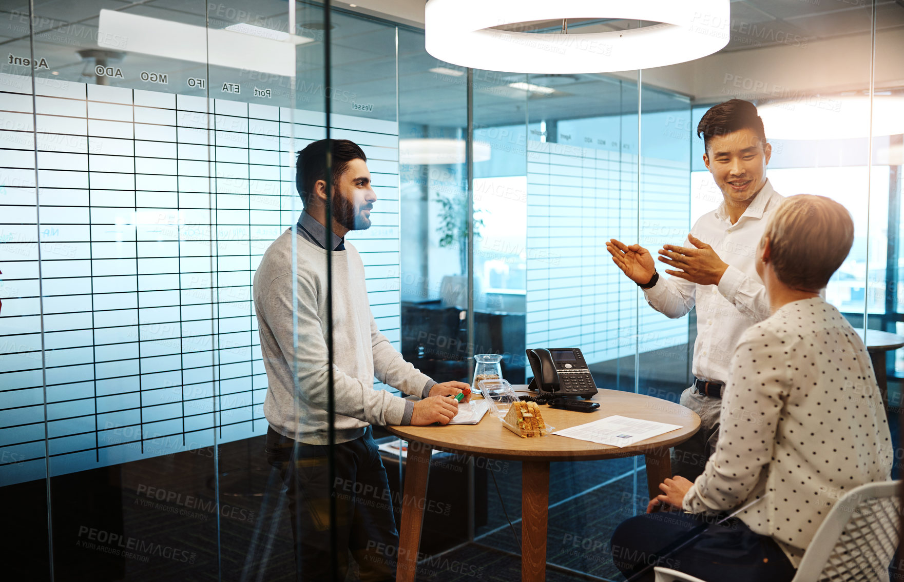 Buy stock photo Cropped shot of three young businesspeople having a meeting in their office