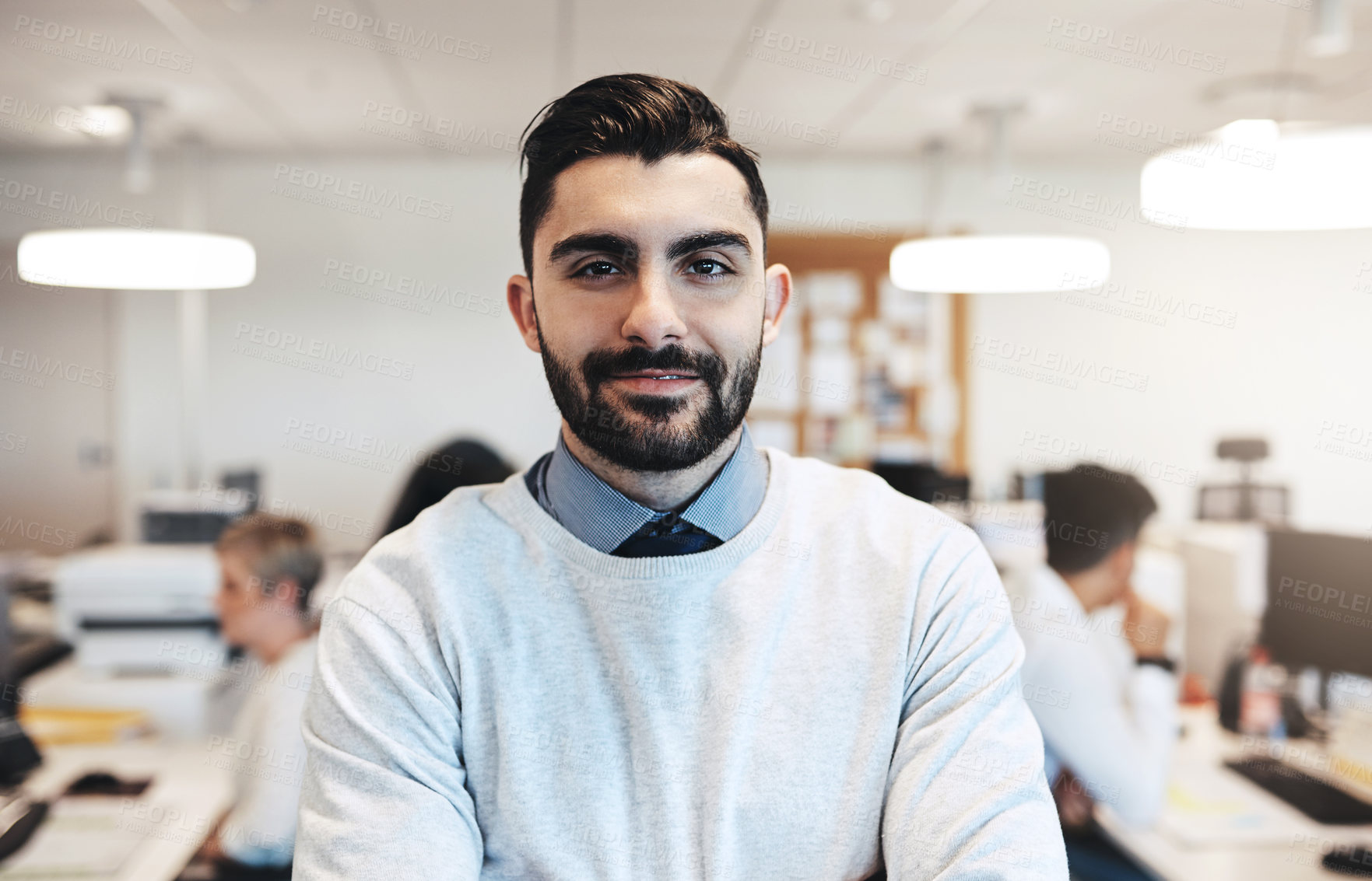 Buy stock photo Cropped portrait of a handsome young businessman in the office while his colleagues are working in the background