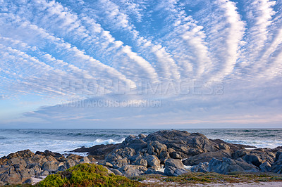 Buy stock photo Copyspace at sea with a cloudy blue sky background and rocky coast in Western Cape South Africa. Ocean waves and boulders at an empty beach. Peaceful scenic landscape for a relaxing summer holiday