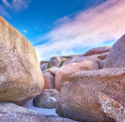 Buy stock photo Texture detail of rock or granite structures at a popular beach location in Cape Town, South Africa. Landscape of large boulders in the sand with a blue cloudy sky in summer with copyspace.