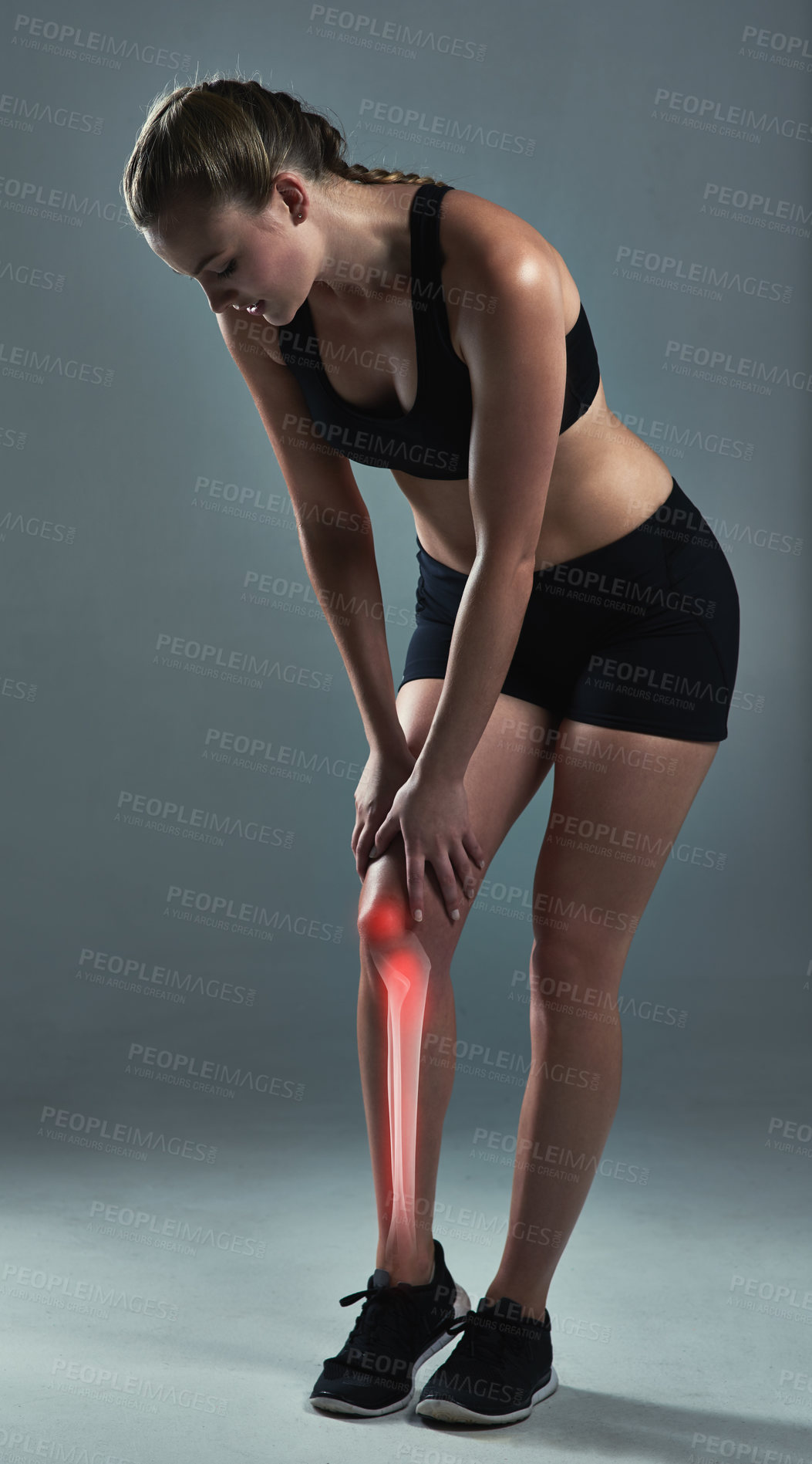 Buy stock photo Studio shot of a sporty young woman suffering from a knee injury