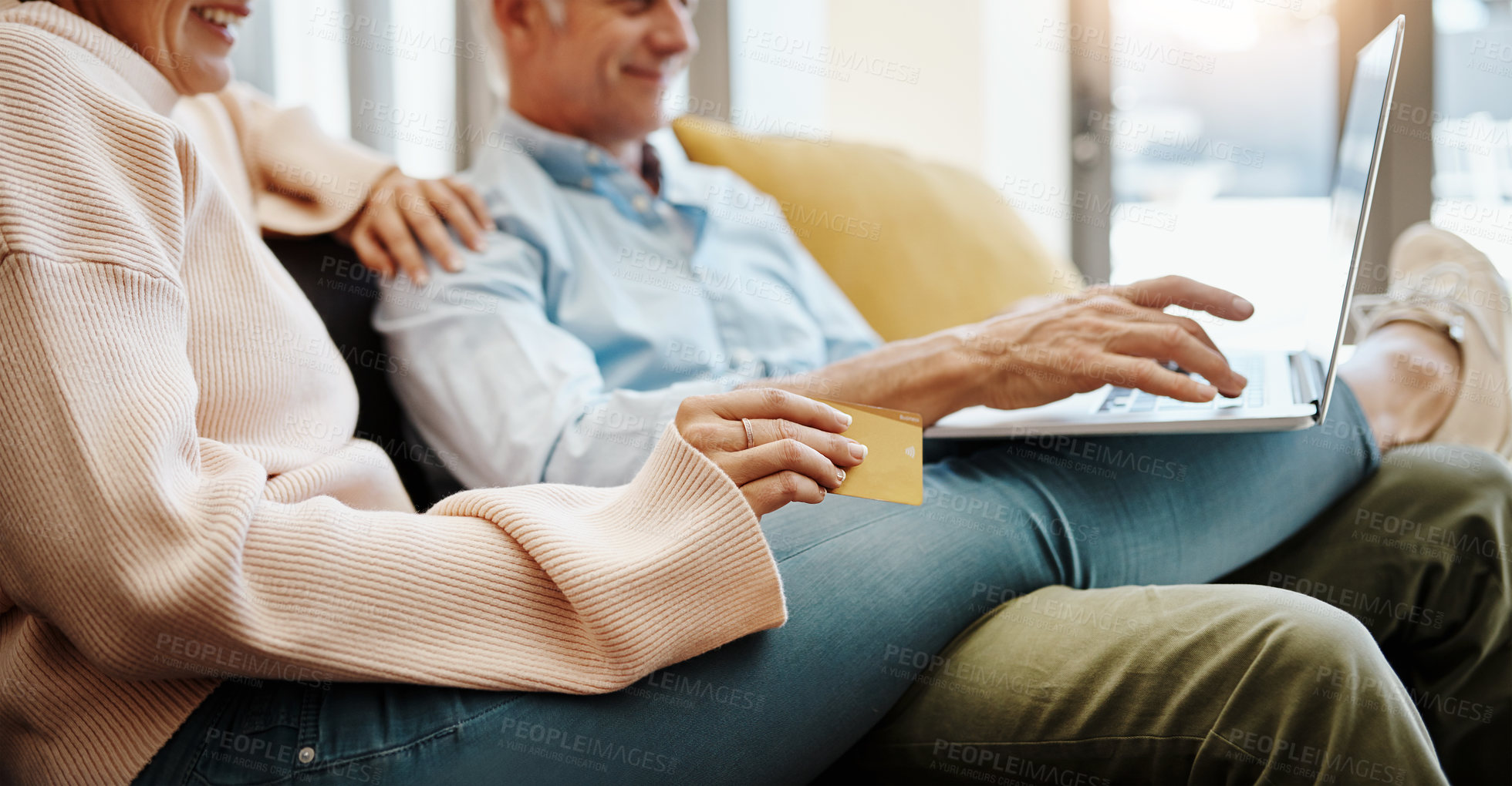 Buy stock photo Shot of a mature couple using a credit card and laptop on the sofa at home