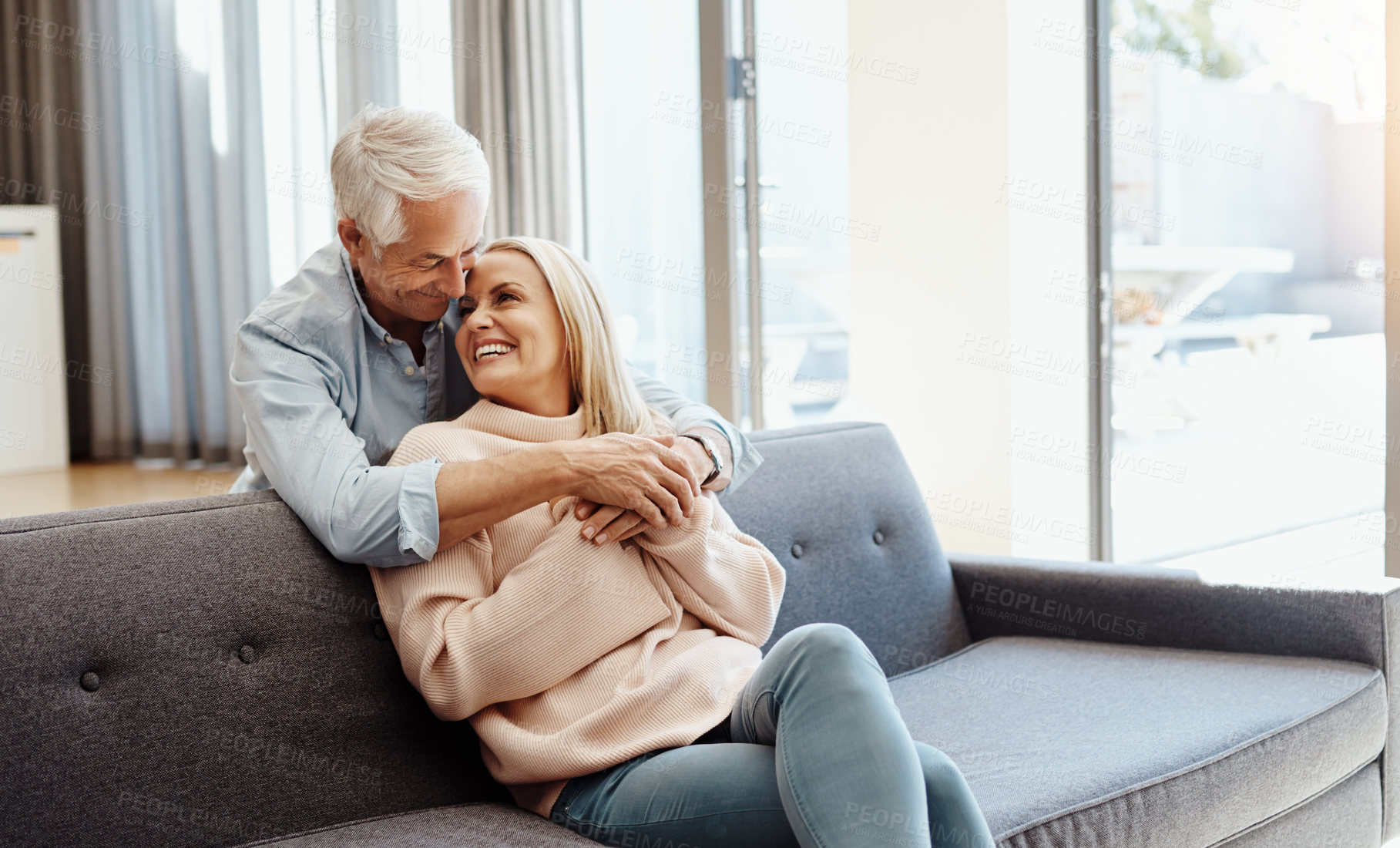 Buy stock photo Shot of a mature man hugging his wife on the sofa at home