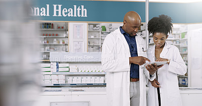 Buy stock photo Cropped shot of two pharmacists using a digital tablet while having a discussion in a chemist