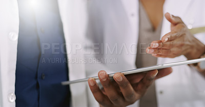 Buy stock photo Closeup shot of two unrecognizable healthcare professionals using a digital tablet while having a discussion