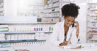 Buy stock photo Shot of an attractive young pharmacist taking notes on a clipboard while on a phonecall