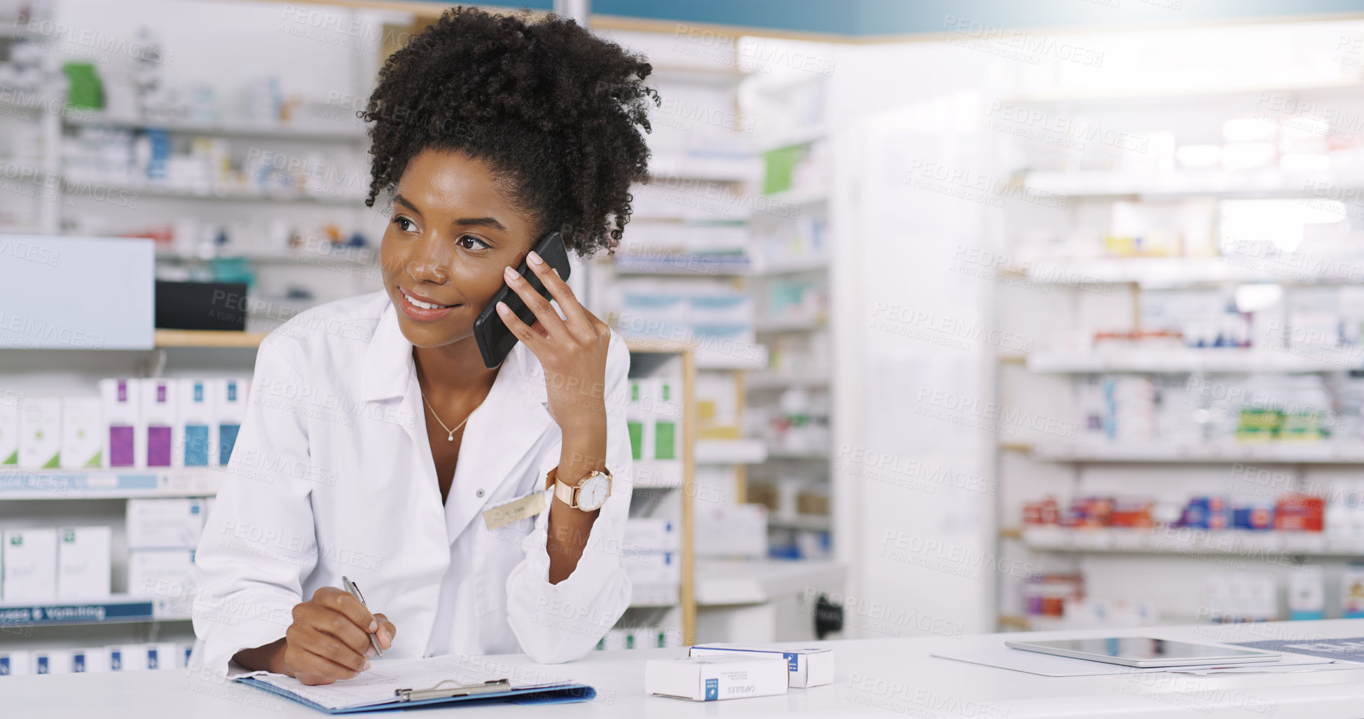 Buy stock photo Shot of an attractive young pharmacist taking notes on a clipboard while on a phonecall