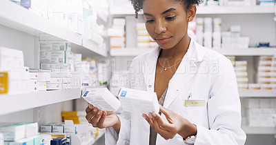 Buy stock photo Cropped shot of an attractive young pharmacist comparing two different types of medication in a chemist