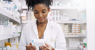 Buy stock photo Cropped shot of an attractive young pharmacist looking at a box of medication in a chemist
