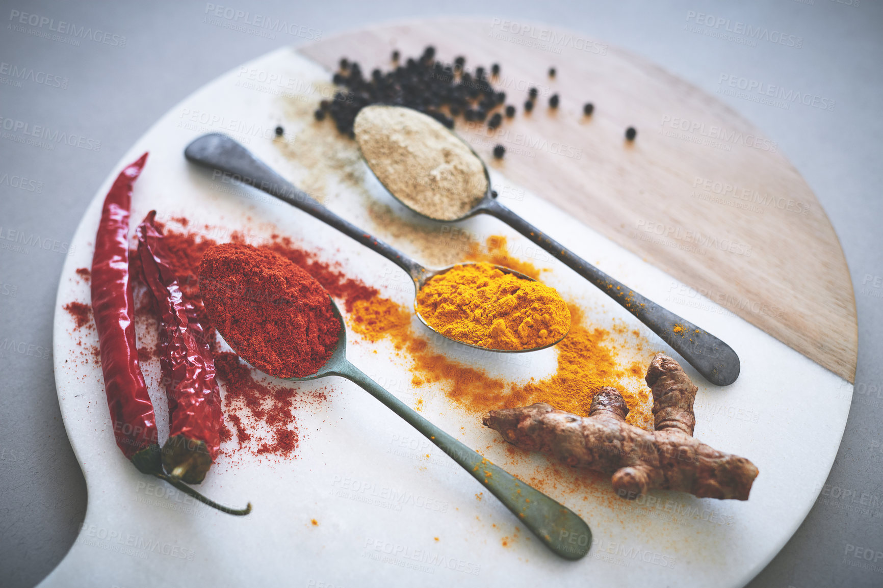 Buy stock photo Board, spices and spoon in gray background for powder, flavor and sensory appeal for creativity with culinary. Studio, condiment and seasoning for cooking with curry, aroma and ingredients collection