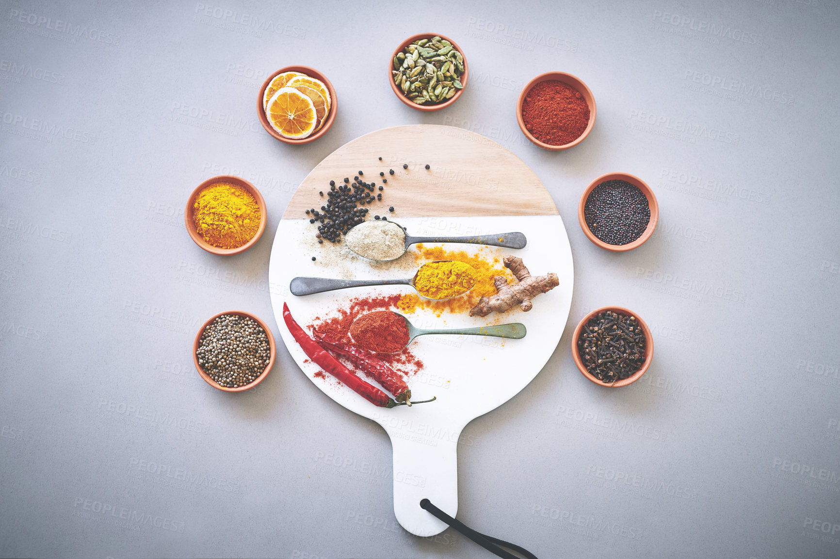 Buy stock photo Spoons, bowl and spices by white background for seasoning, powder or board for sensory appeal with culinary. Top, condiment or flavor for cooking with coriander, black pepper or curry for ingredients