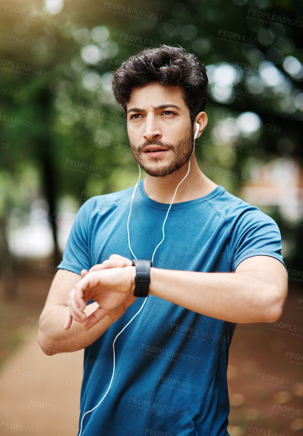 Buy stock photo Shot of a sporty young man listening to music while exercising outdoors