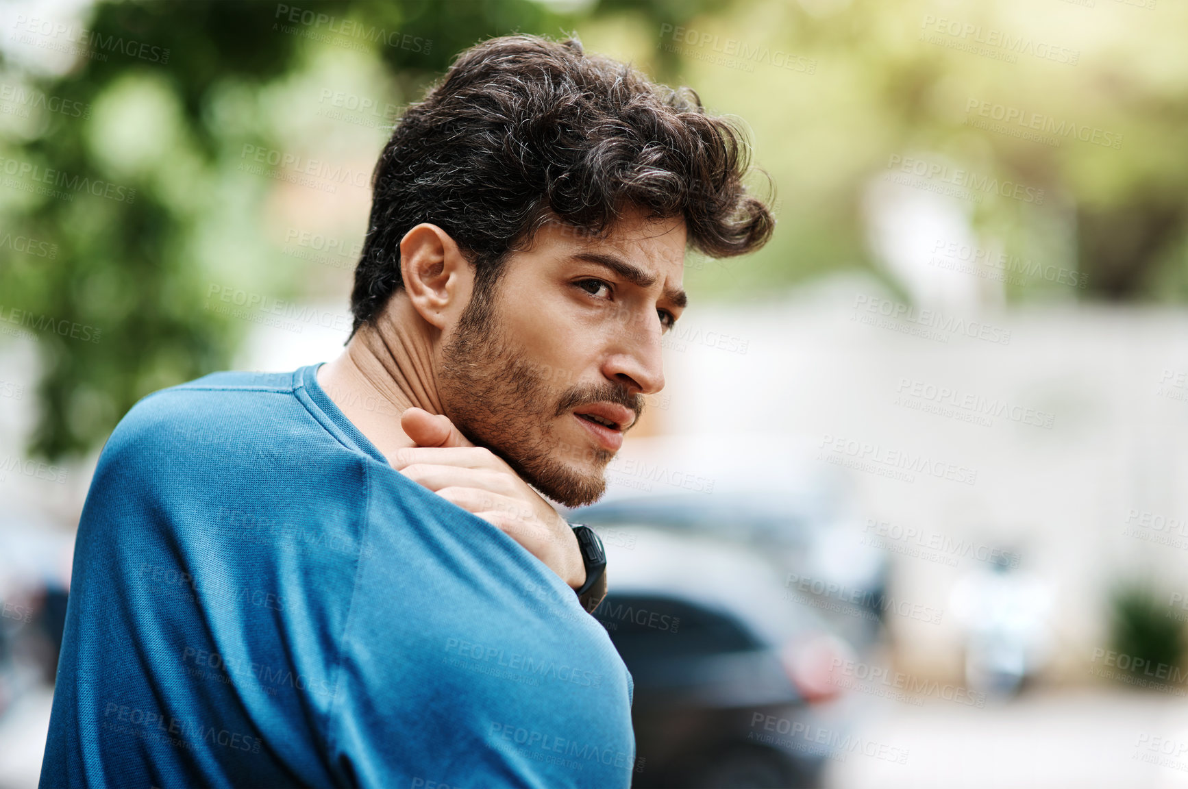 Buy stock photo Shot of a sporty young man holding his shoulder in pain while exercising outdoors