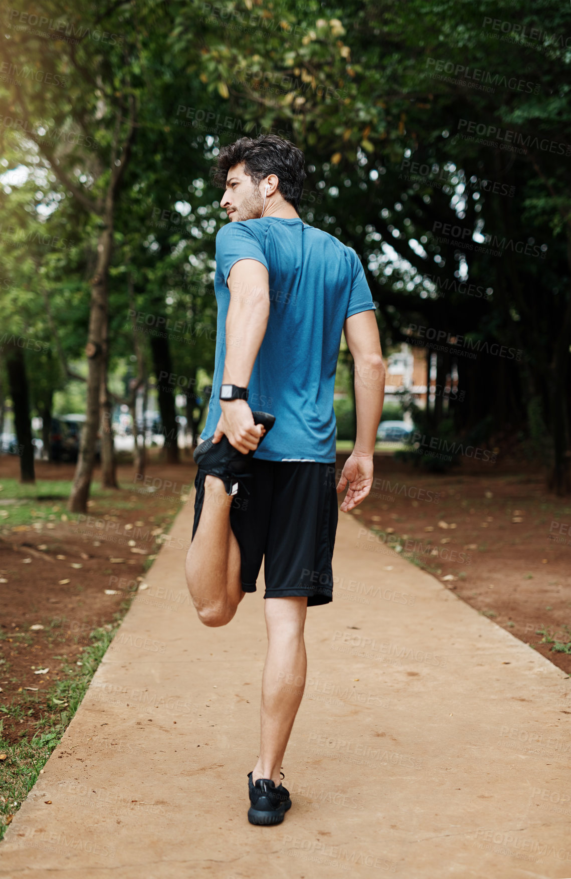 Buy stock photo Shot of a sporty young man stretching his legs while exercising outdoors