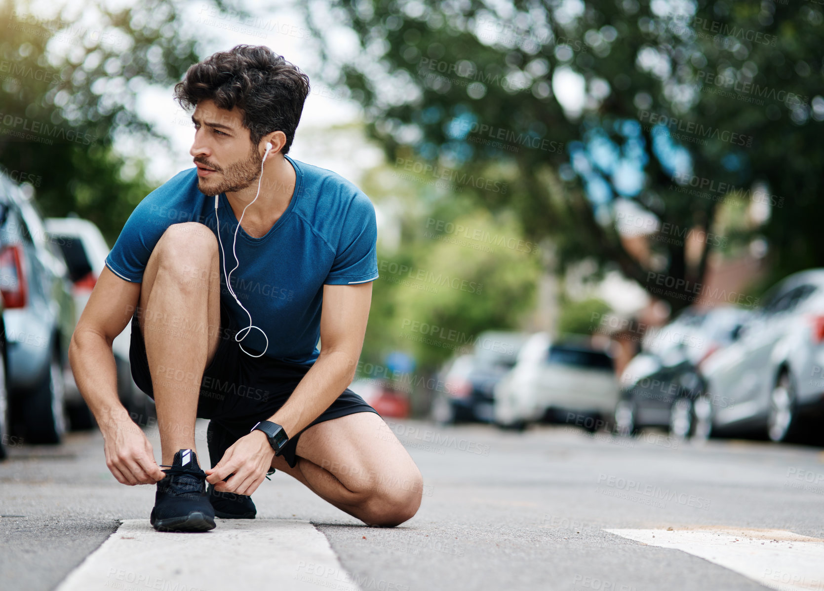 Buy stock photo Shot of a sporty young man tying his shoes before going for a jog outside during the day