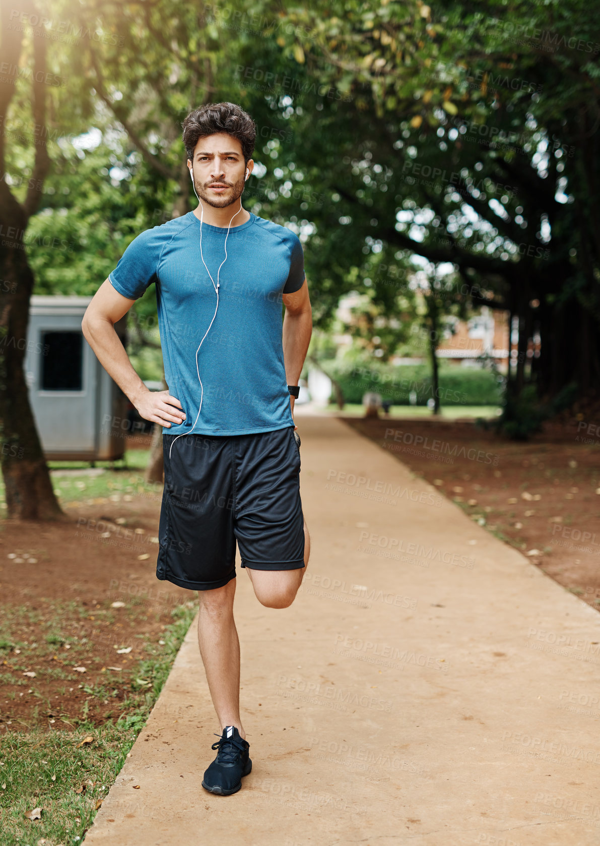 Buy stock photo Shot of a sporty young man stretching his legs while exercising outdoors