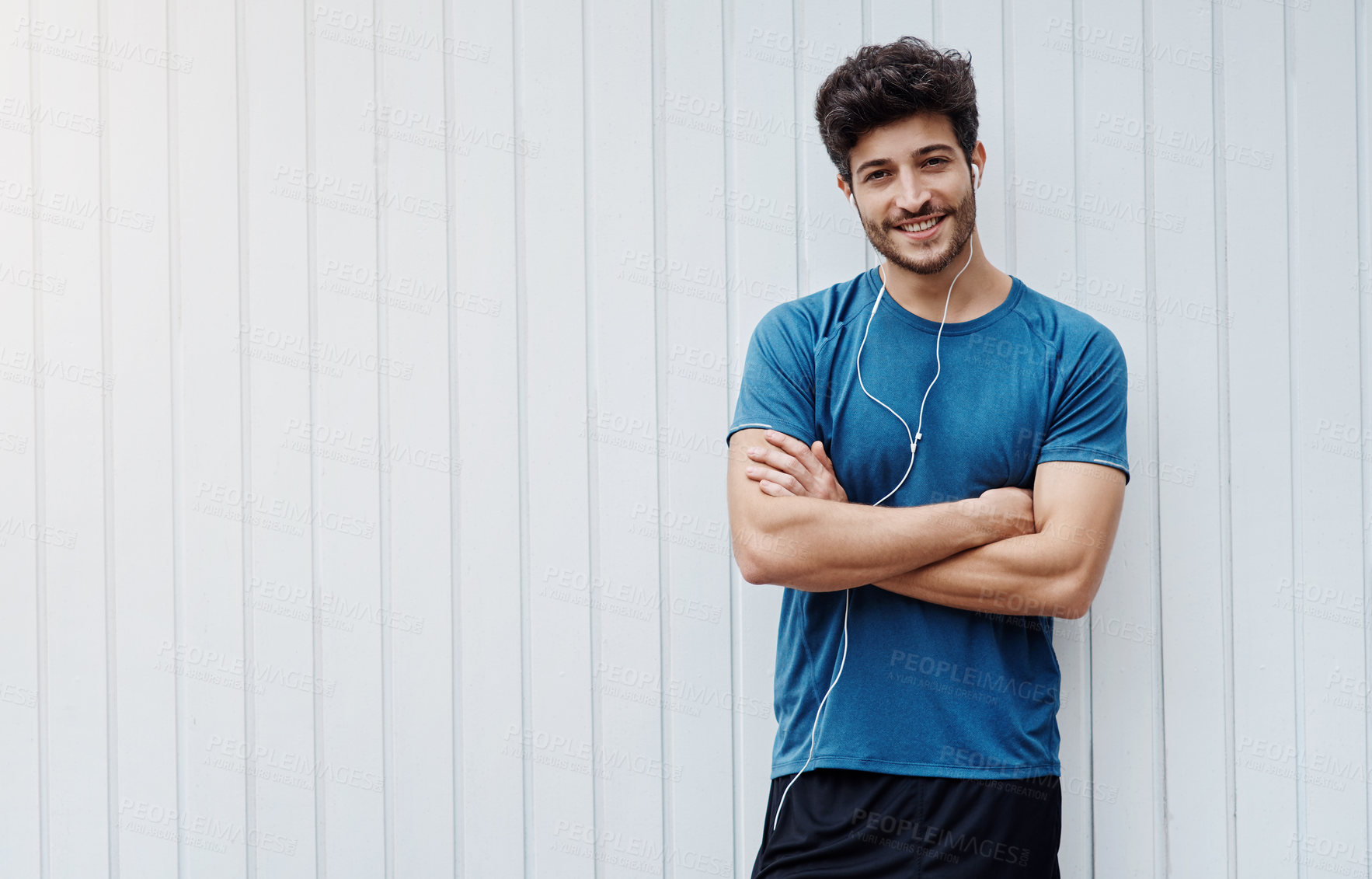 Buy stock photo Portrait of a sporty young man standing against a white wall after exercising outside during the day