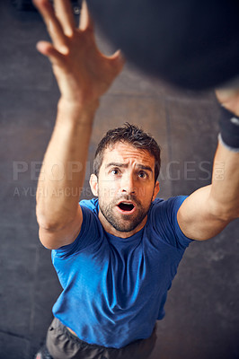 Buy stock photo High angle shot of a handsome young man working out with a medicine ball in the gym