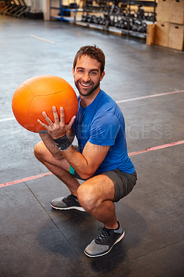 Buy stock photo High angle portrait of a handsome young man working out with a medicine ball in the gym
