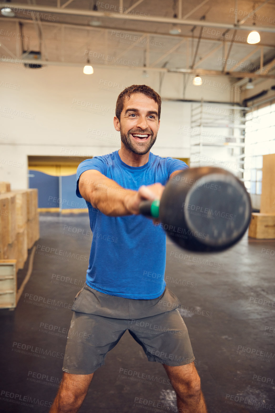 Buy stock photo Cropped shot of a handsome young man working out with a kettle bell in the gym