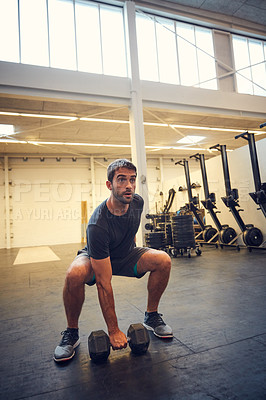 Buy stock photo Full length shot of a handsome young man working out with a dumbbell in the gym