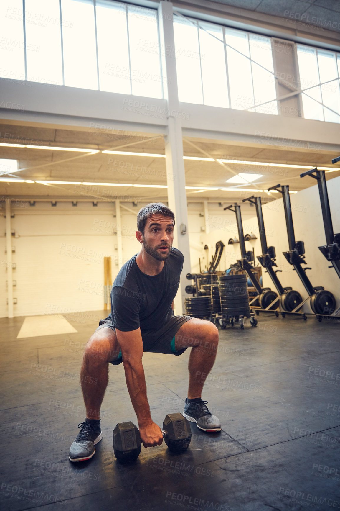 Buy stock photo Full length shot of a handsome young man working out with a dumbbell in the gym